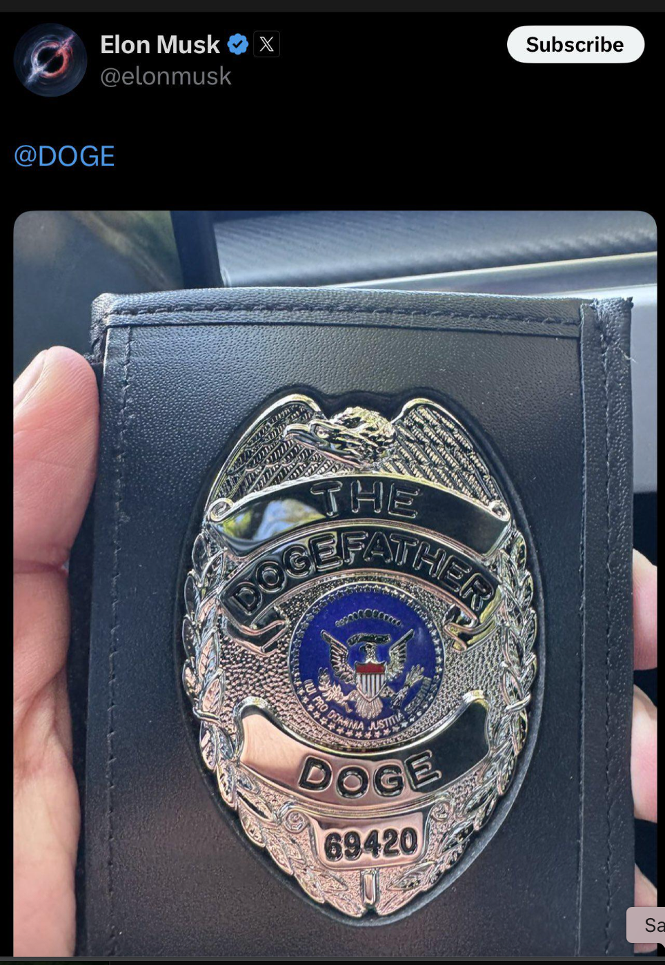 A hand holds a badge labeled &quot;The Dogefather&quot; with an emblem and text &quot;Doge 69420,&quot; shared by an account named Elon Musk