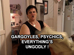 A person enthusiastically gesturing in a room with the text, "Gargoyles, psychics, everything's ungodly!" displayed over the scene