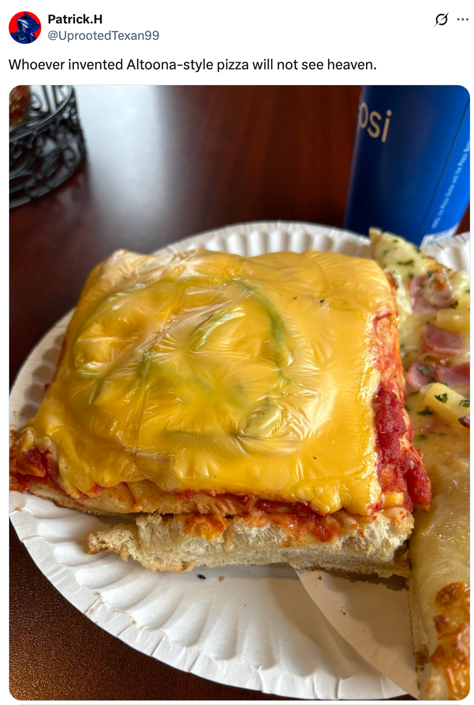 Cheese-covered, thick-crust pizza slice with tomato sauce on a paper plate next to a Pepsi can, taken in a casual setting