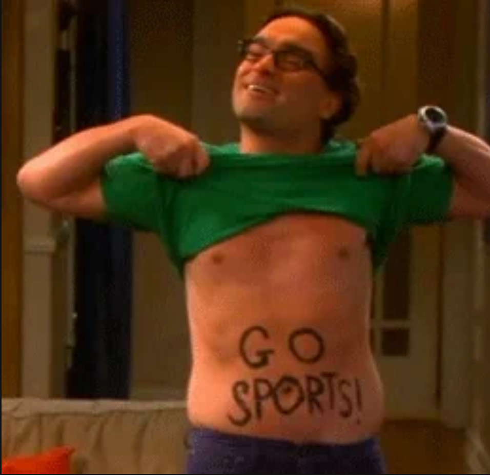 Man on TV comedy lifts shirt, revealing "GO SPORTS!" written on his stomach in a playful scene