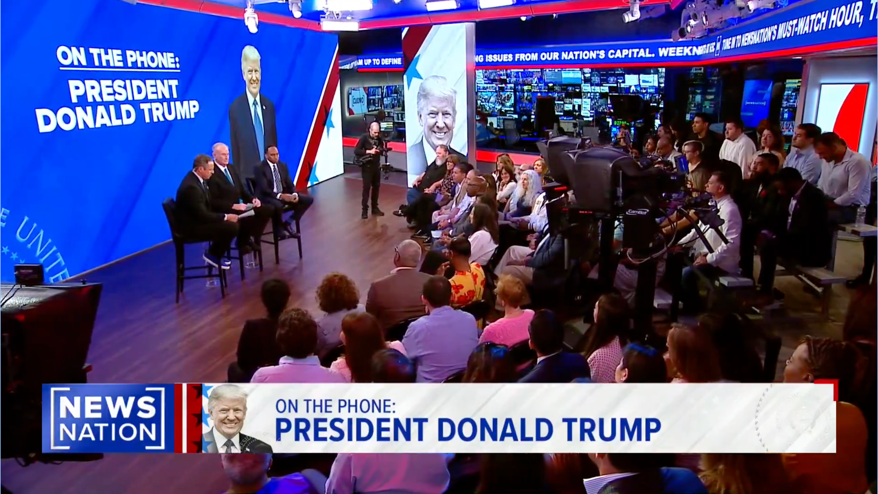 TV studio audience watches a live broadcast of a talk show, featuring Donald Trump on the phone, with hosts on stage discussing current events