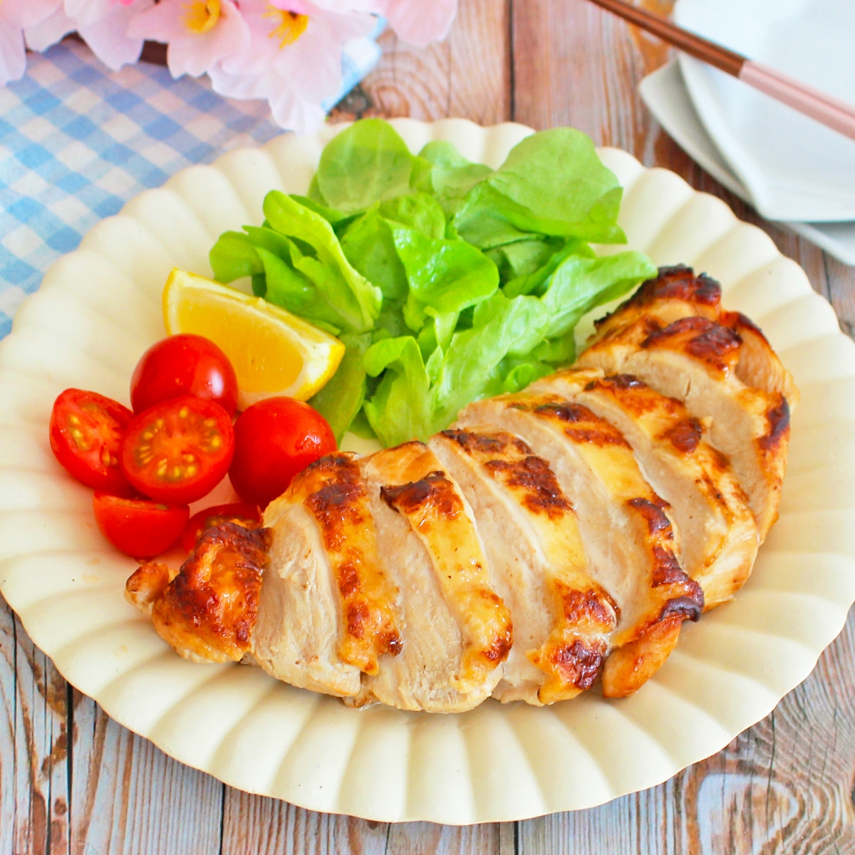 グリルチキン、レタス、ミニトマト、レモンが盛り付けられた皿。