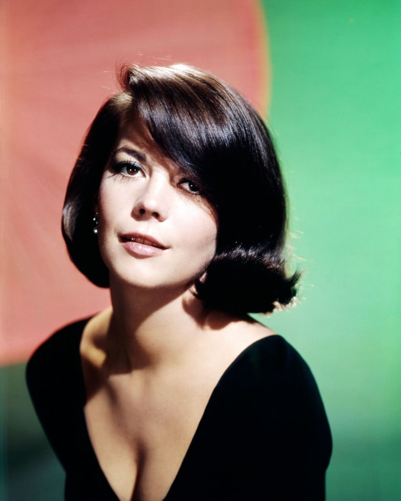 Person with a classic bob hairstyle gazes forward, wearing elegant attire