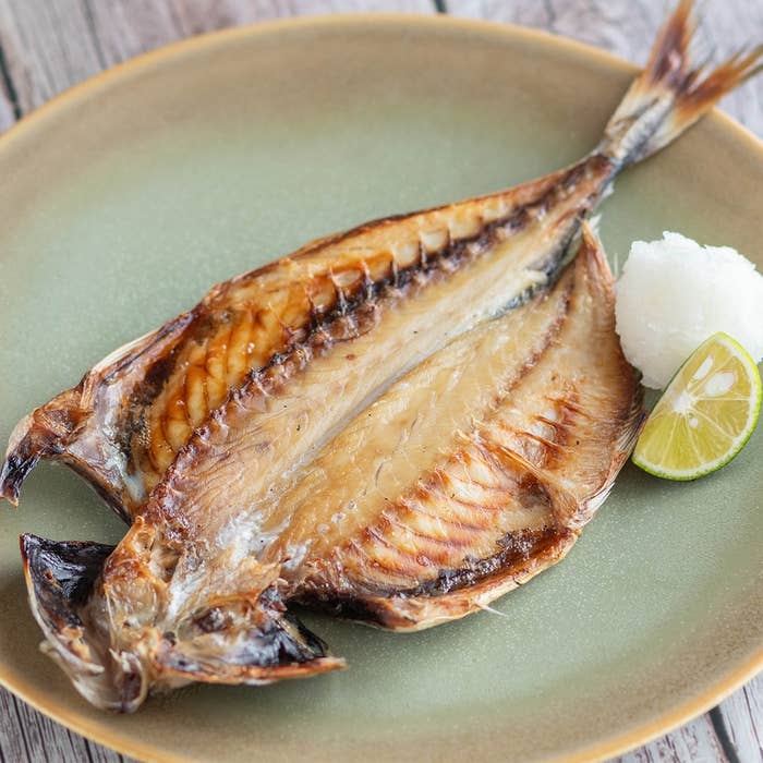 焼き魚が皿に盛られ、大根おろしとライム添え。おいしい和食の一例。