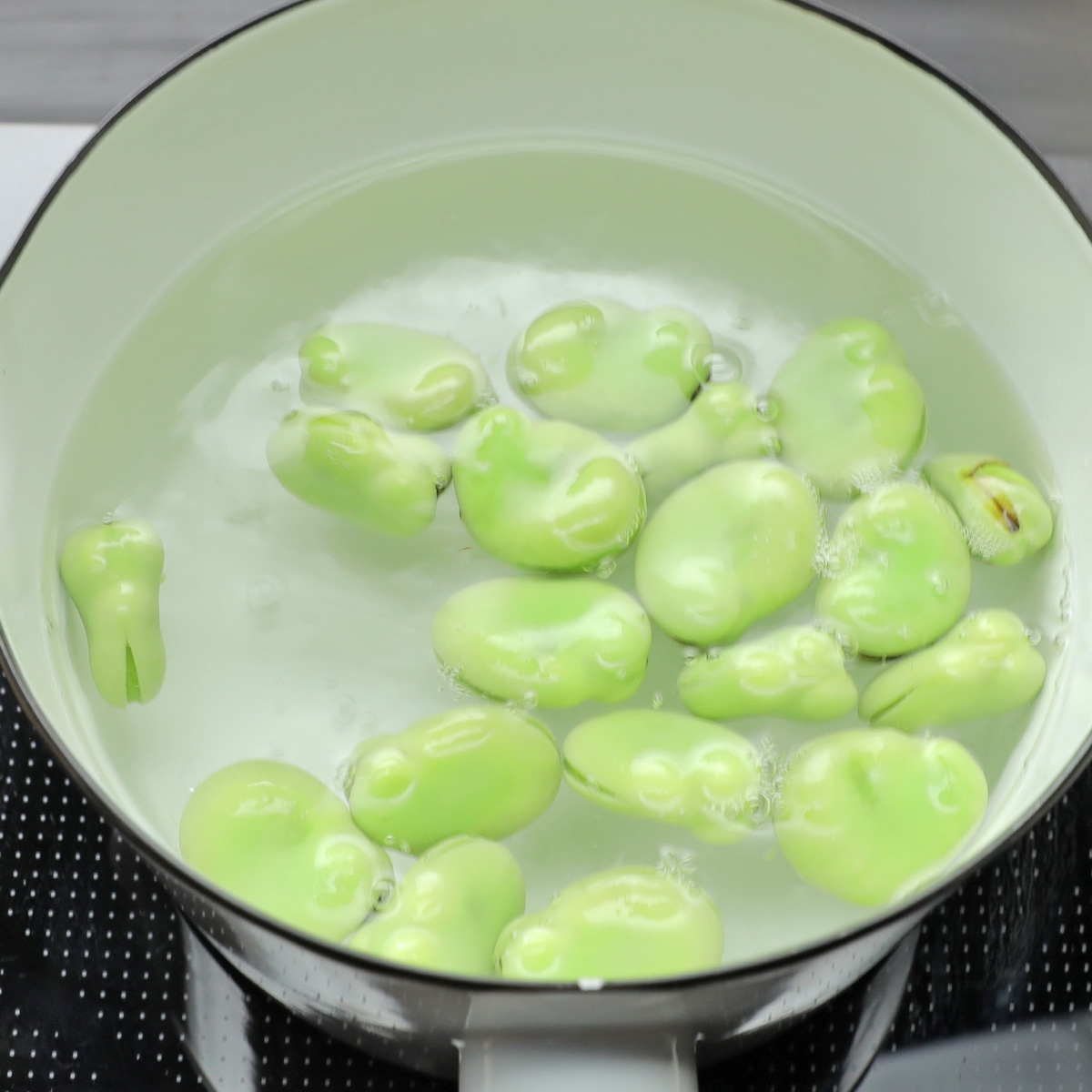 鍋で茹でられているそら豆。