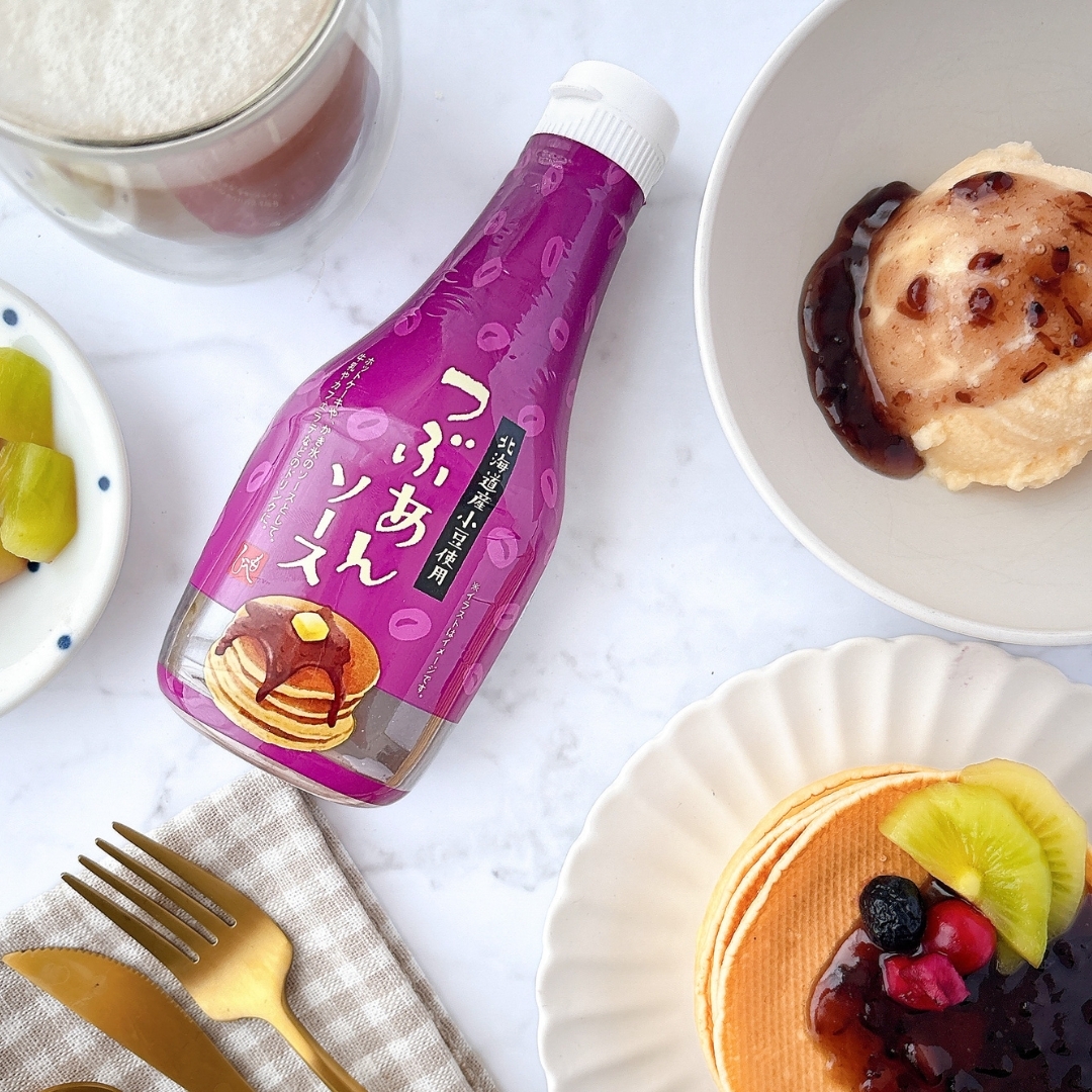 パンケーキとクリームに、紫色の瓶のつぶあんソースが添えられたテーブルのセッティング。