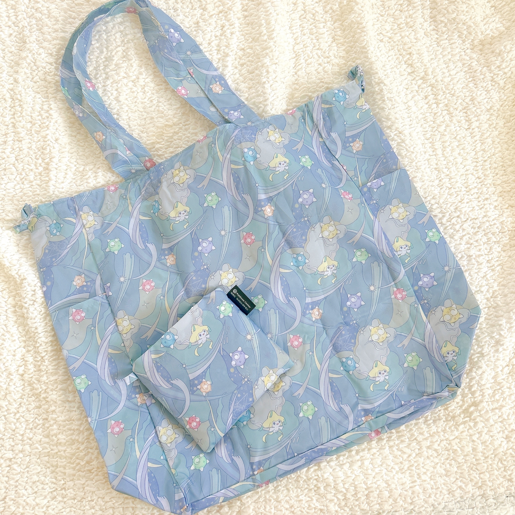 プリント柄のエコバッグと小さなポーチがセットになっています。バッグはキャラクターデザインで、柔らかい素材感が特徴です。