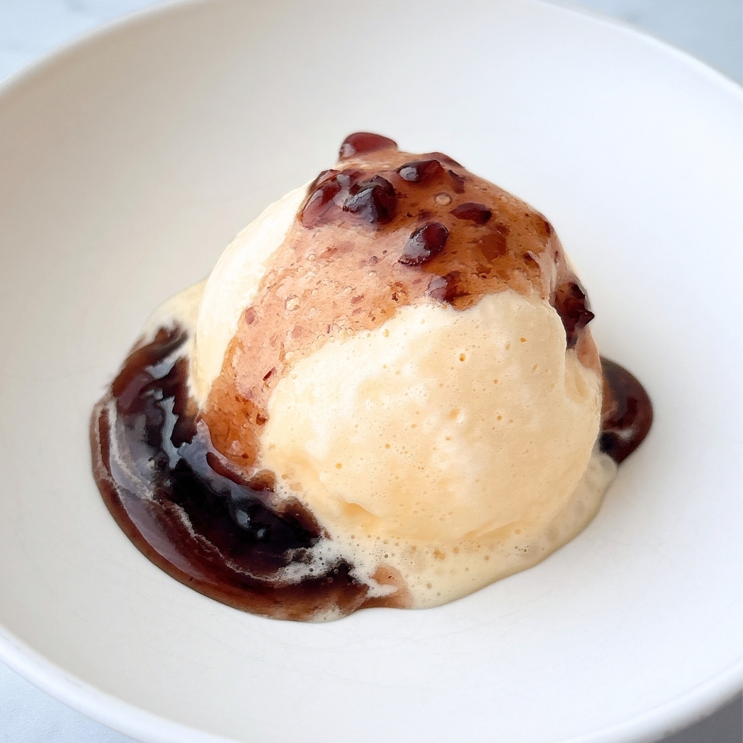 ボウルに盛られたアイスクリームにチョコレートソースがかかっています。