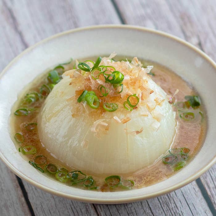 皿に盛られた大根の煮物。上には刻みネギと削り節がのっている。日本料理の一品。