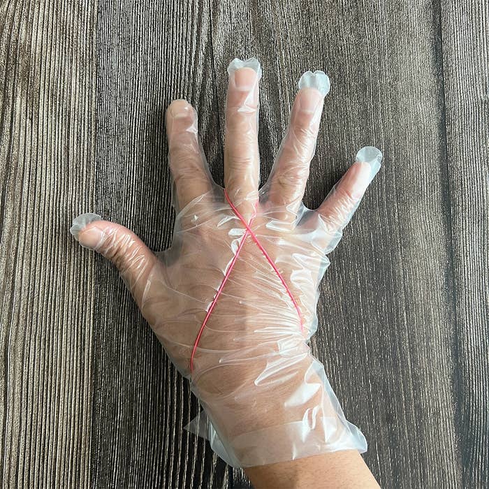手に透明なビニール手袋を装着し、赤いゴムバンドがかかっている様子。