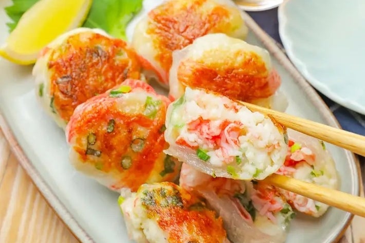 和風の銀色の皿に盛られた焼き餃子。箸で持ち上げた餃子の断面には具材が見える。食欲をそそる一品。