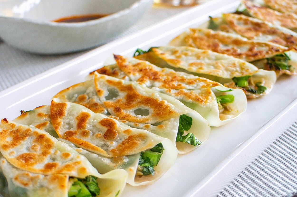 皿に盛られた焼き餃子が並んでおり、ソースとビールのグラスが背景にある。