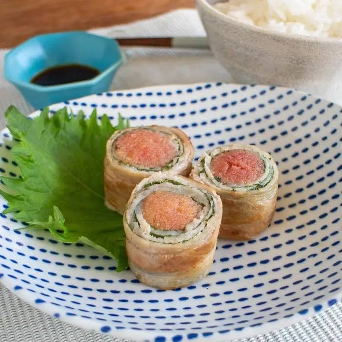 皿に盛られた、しその葉で飾られた三つのトルティーヤ風寿司ロール。隣に醤油とご飯がある。