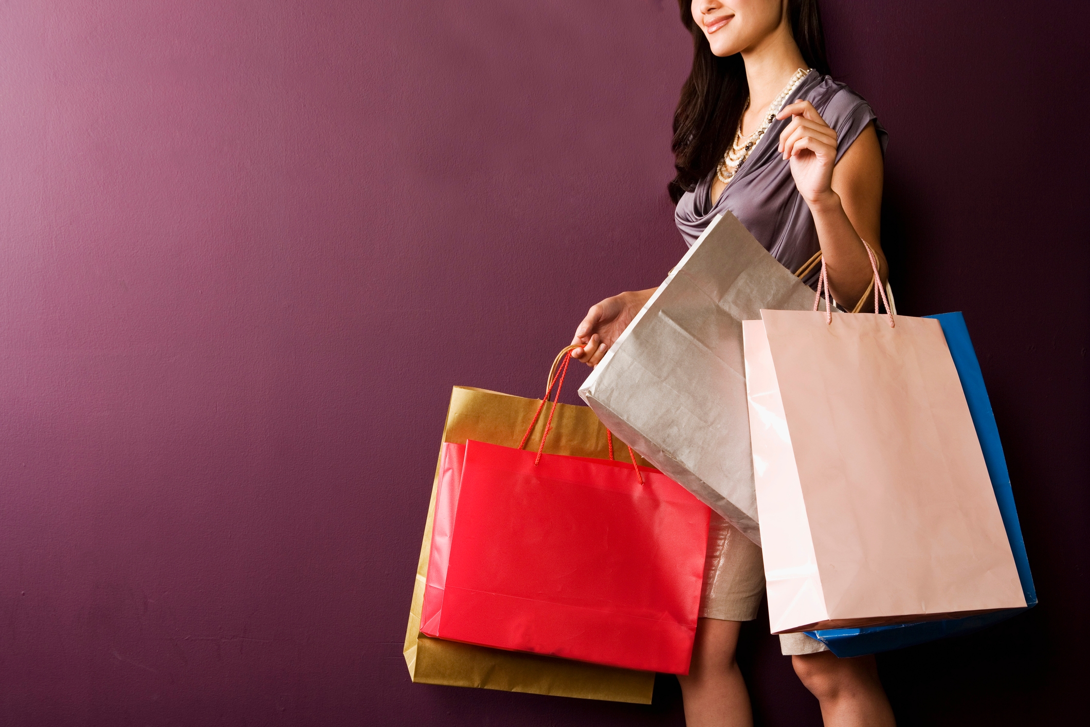 Person holding multiple shopping bags, suggesting a shopping spree or consumerism theme