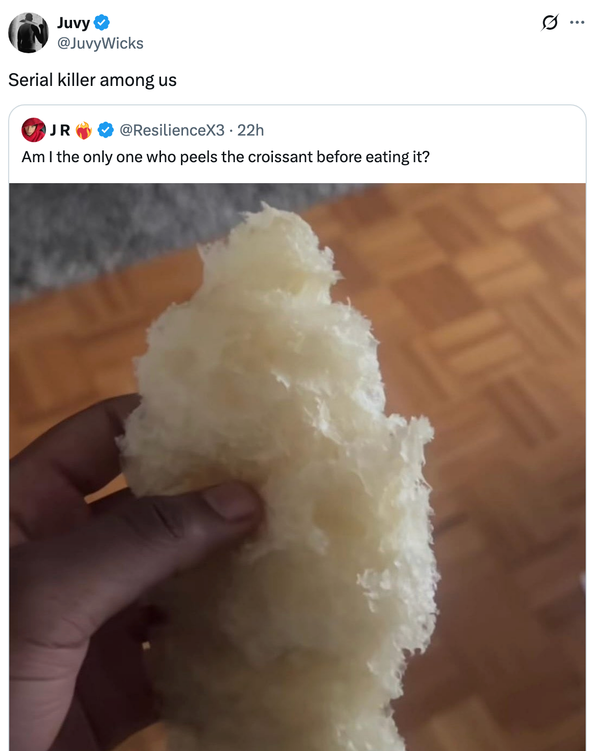 A hand holds a peeled croissant, revealing its fluffy inner layers. The image caption humorously refers to the act as unusual behavior