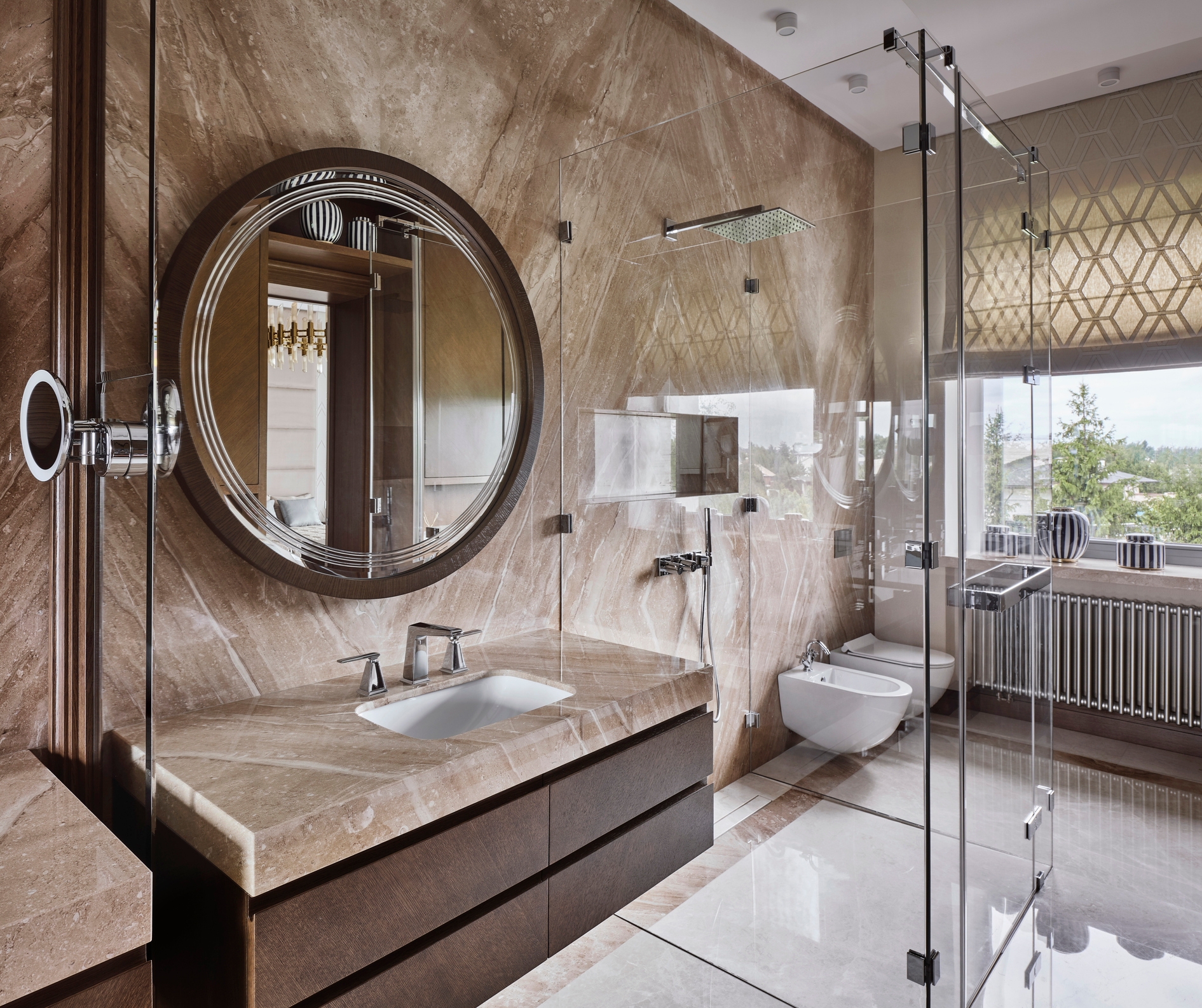 Luxurious bathroom with marble walls, round mirror, and glass shower enclosure, highlighting modern design and opulence