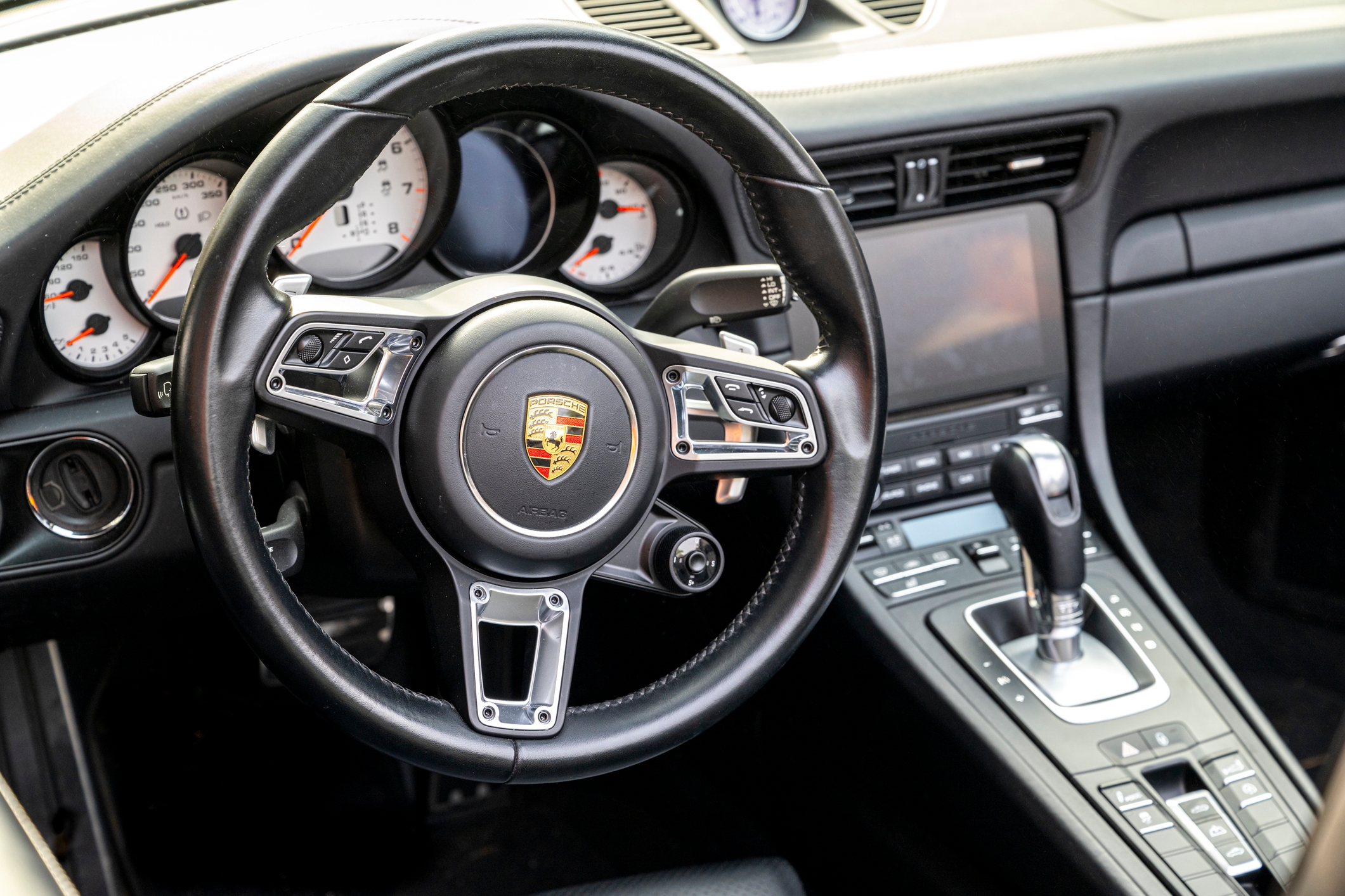 Luxury car interior featuring a Porsche steering wheel and dashboard
