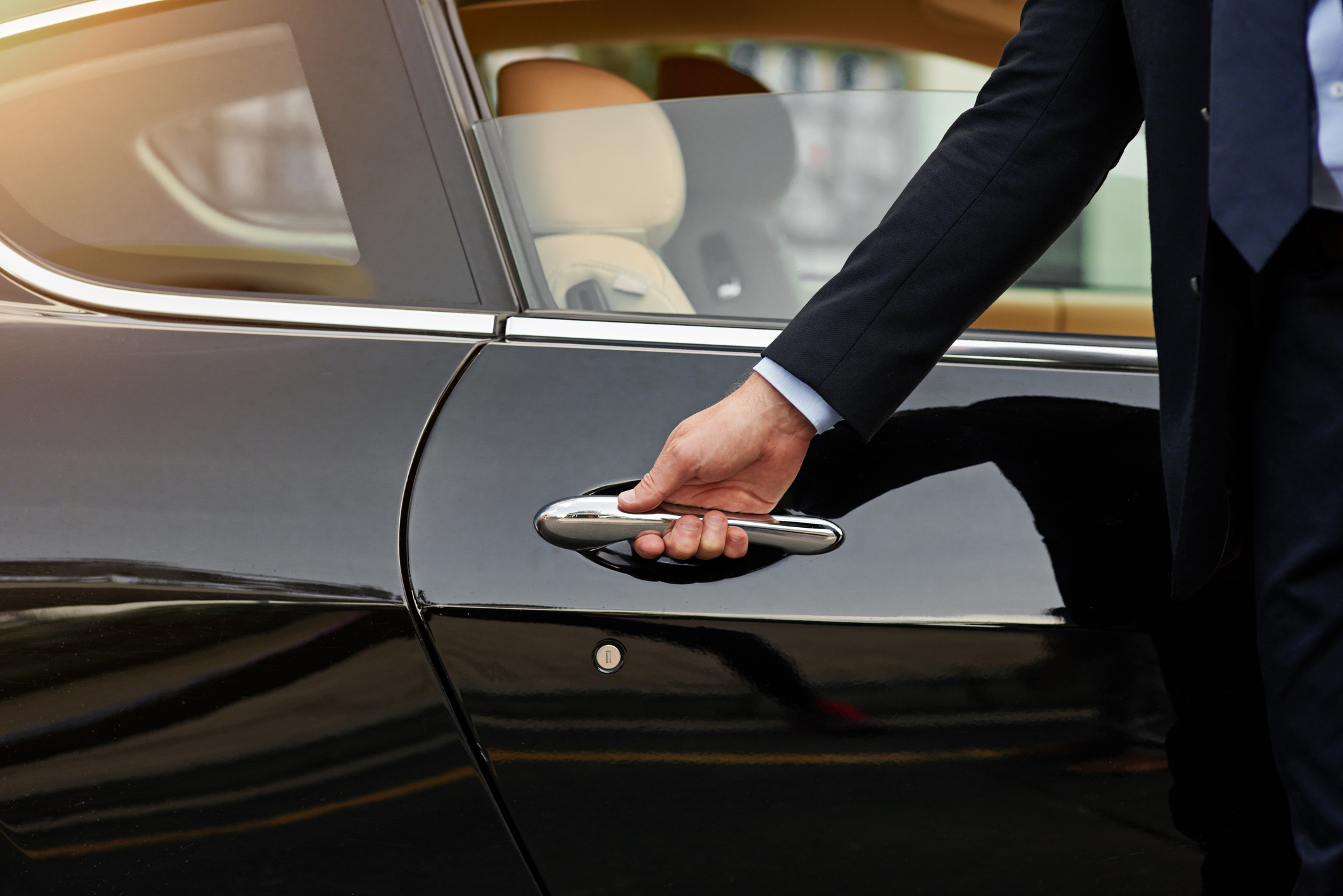 Person in a suit opening a car door, depicting a professional or business context