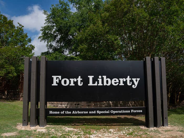 Sign reading "Fort Liberty: Home of the Airborne and Special Operations Forces" set in a green, wooded area