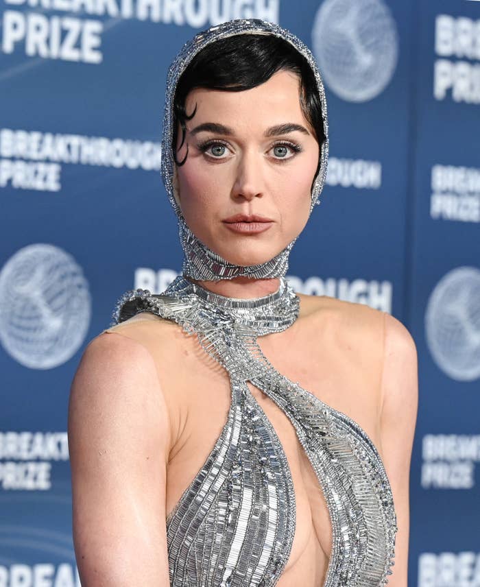 Person on red carpet in shimmering, futuristic gown with intricate detailing and headpiece, attending the Breakthrough Prize event