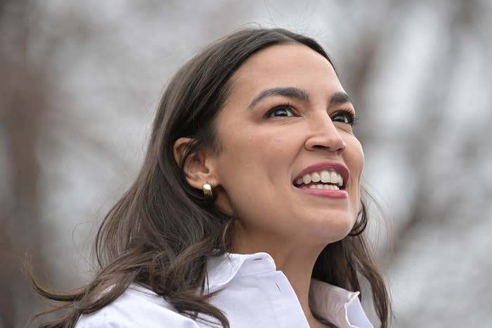 Person outdoors, smiling, wearing a white collared shirt and pearl earrings