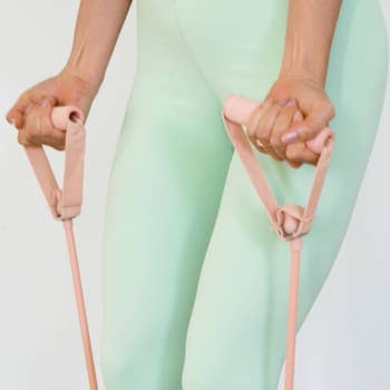 Person exercising with absorption bands, focusing connected arms and hands gripping the handles