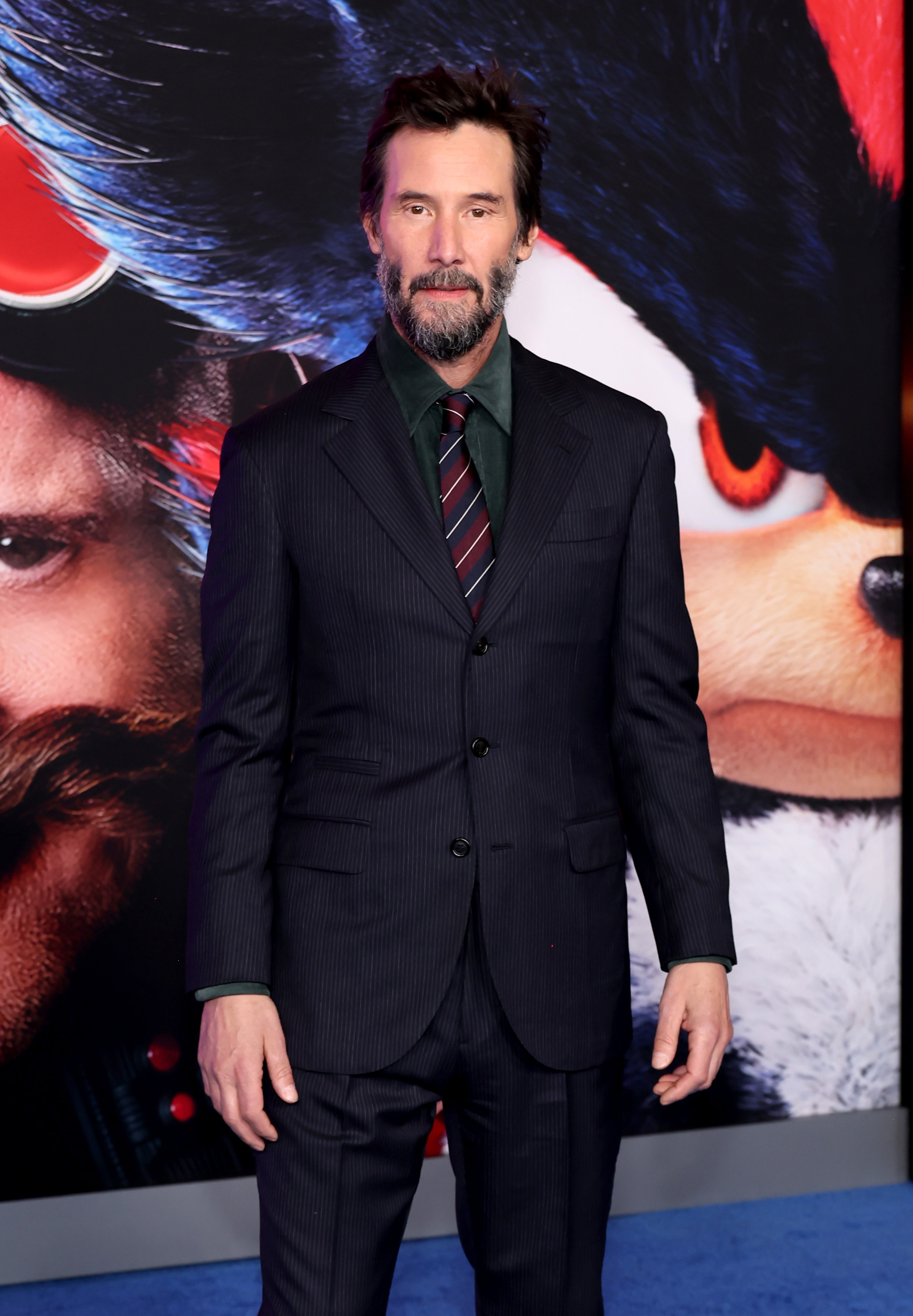 Person in pinstripe suit and tie at a movie premiere event with a film poster backdrop