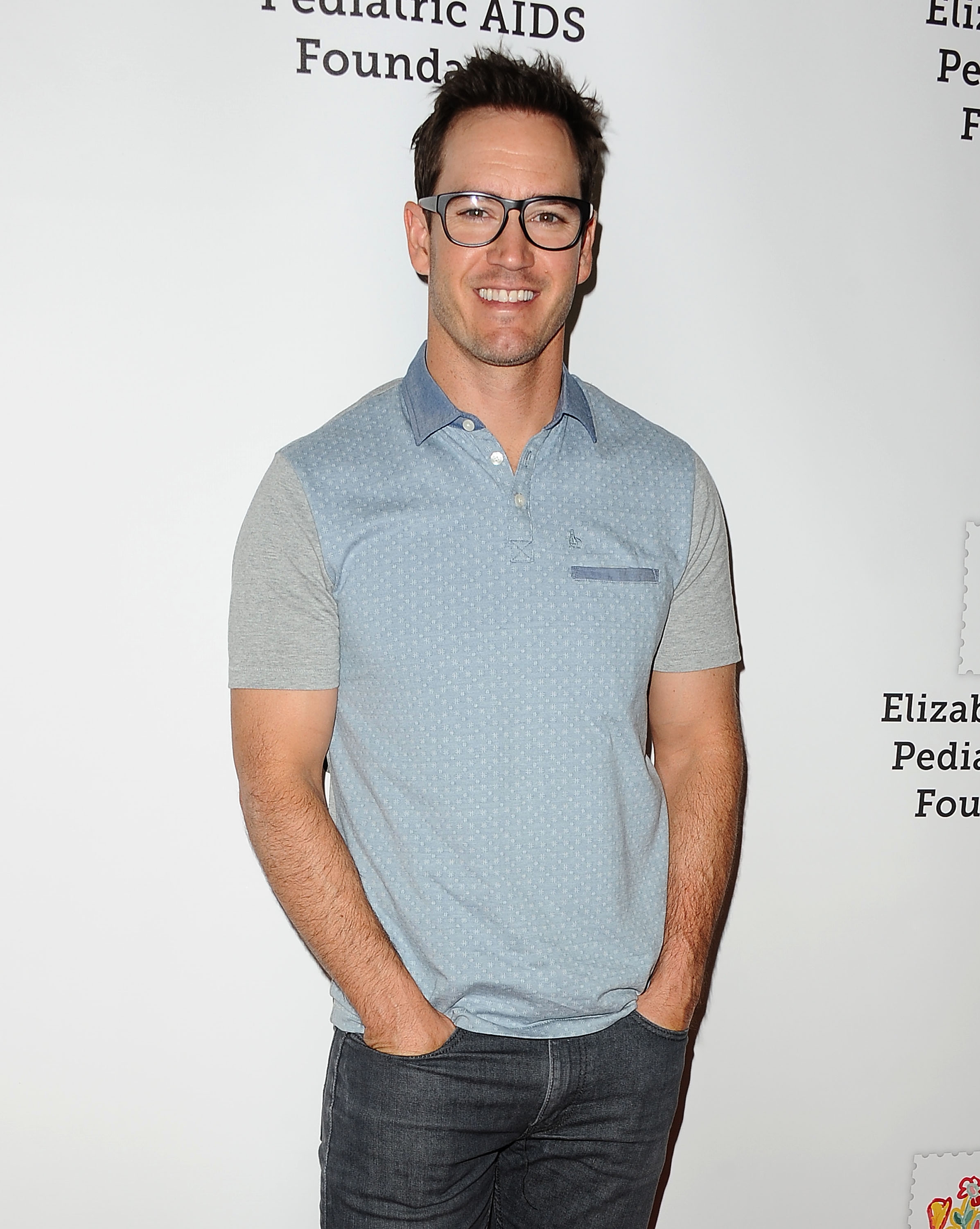 Person in a casual polo shirt and jeans at a Pediatric AIDS Foundation event, smiling for the camera