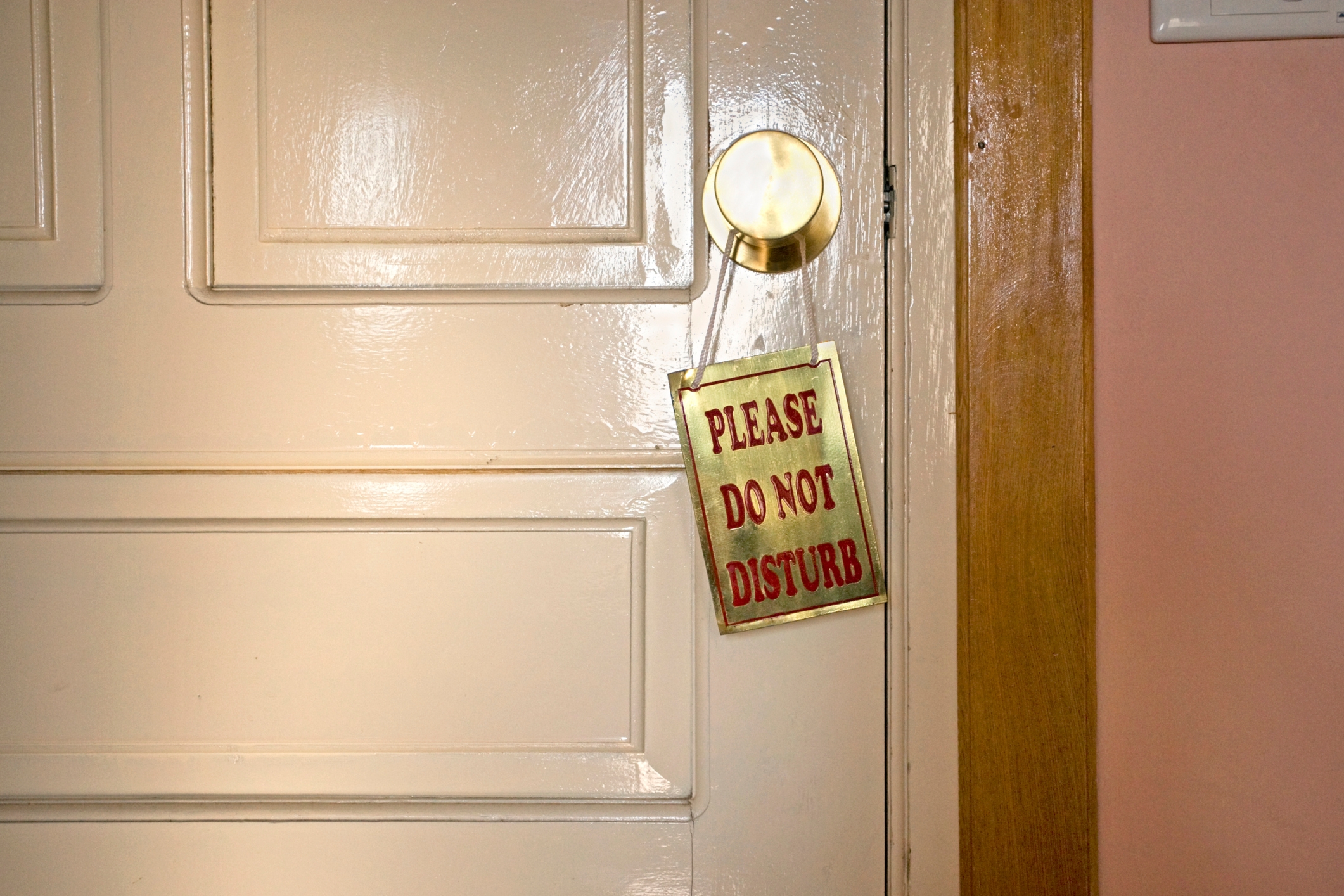 A door with a "Please Do Not Disturb" sign hanging from the knob