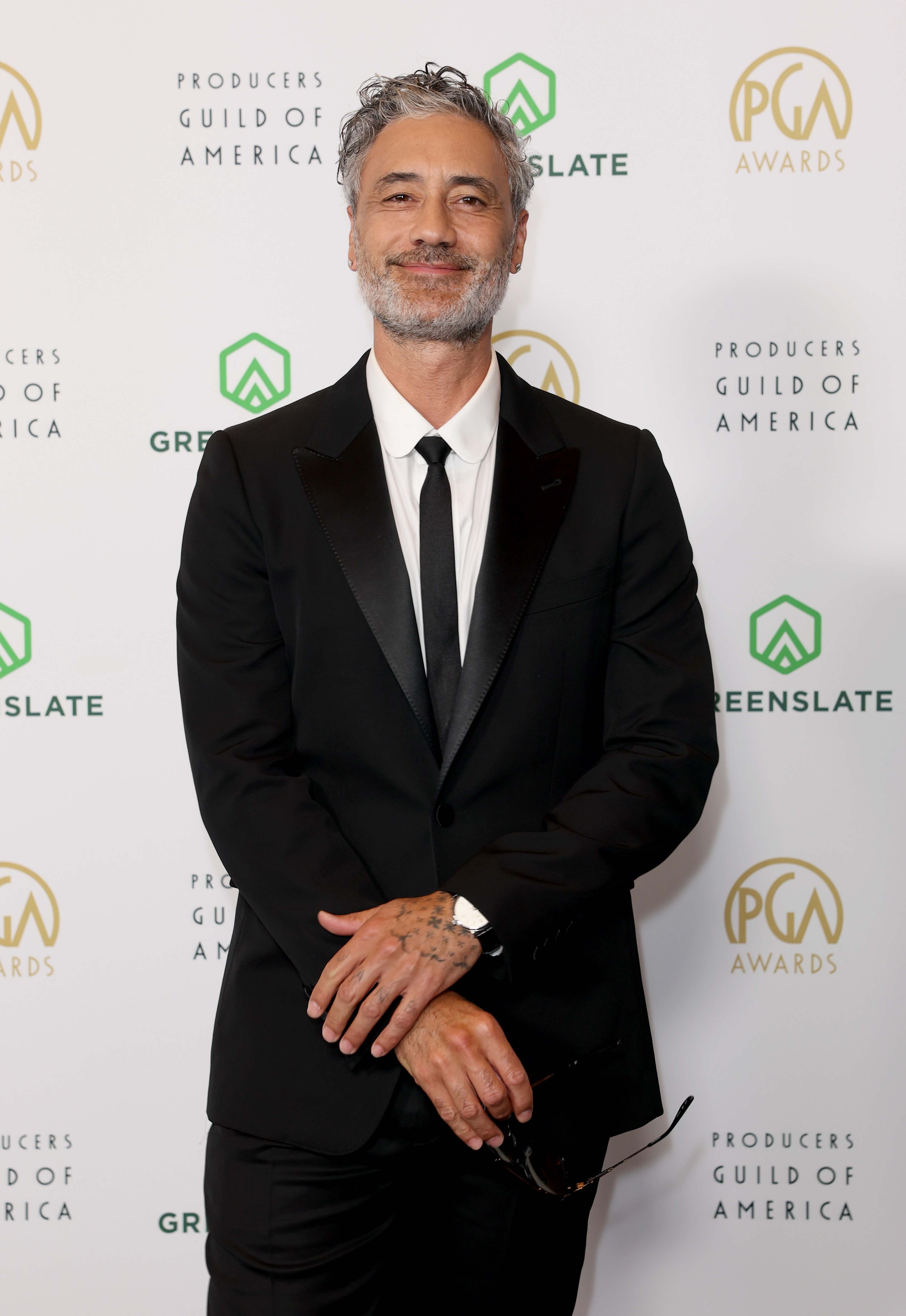 Person in a black suit and tie on the red carpet at the Producers Guild of America event