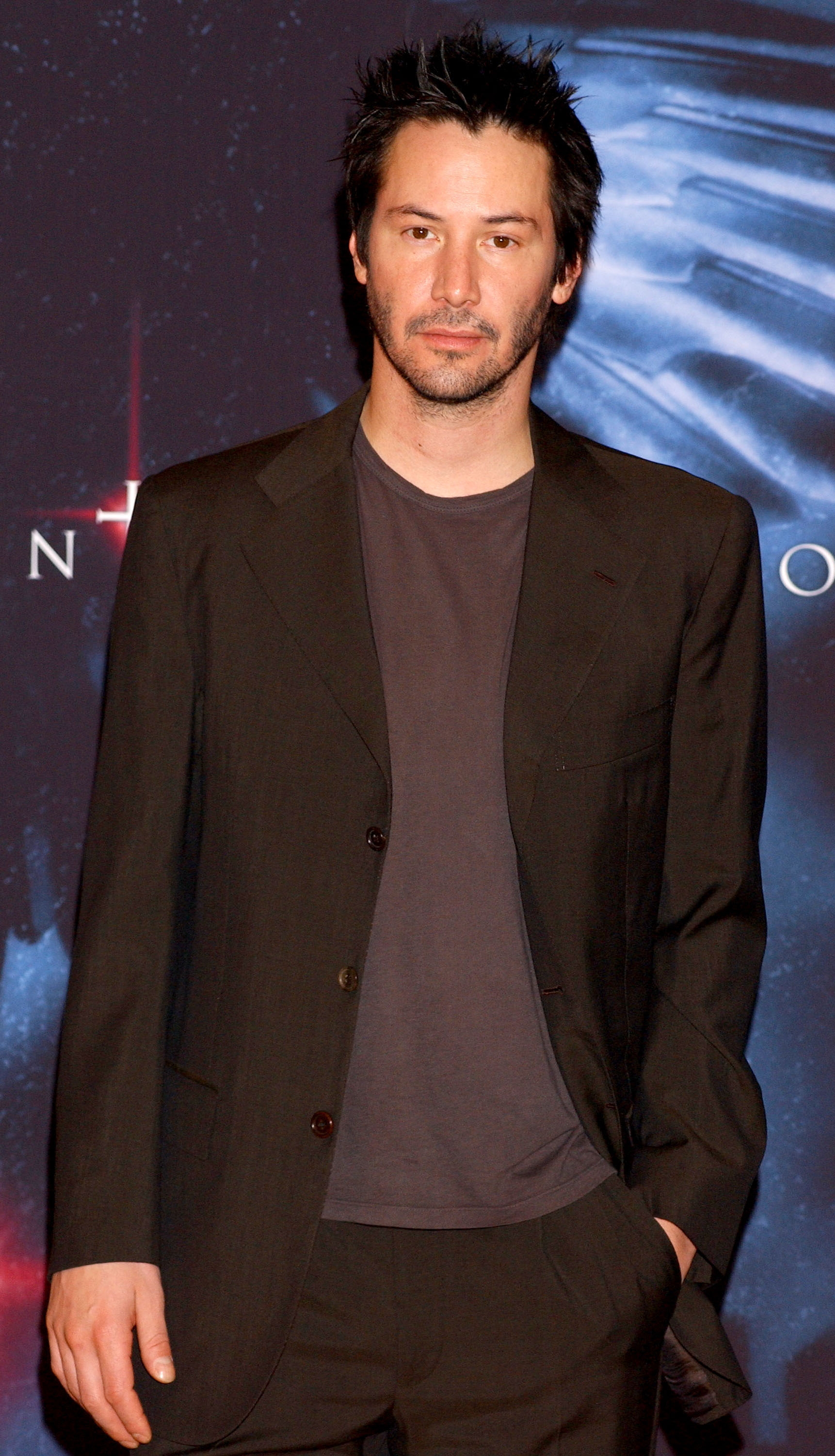 Person in a relaxed-fit suit on a red carpet event. They have short, tousled hair and a casual, confident stance