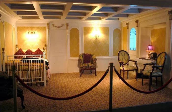 Room styled to resemble early 20th-century luxury setting with vintage furniture and decor, separated by a red rope