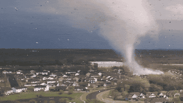 large tornado moving quickly over buildings, destroying them