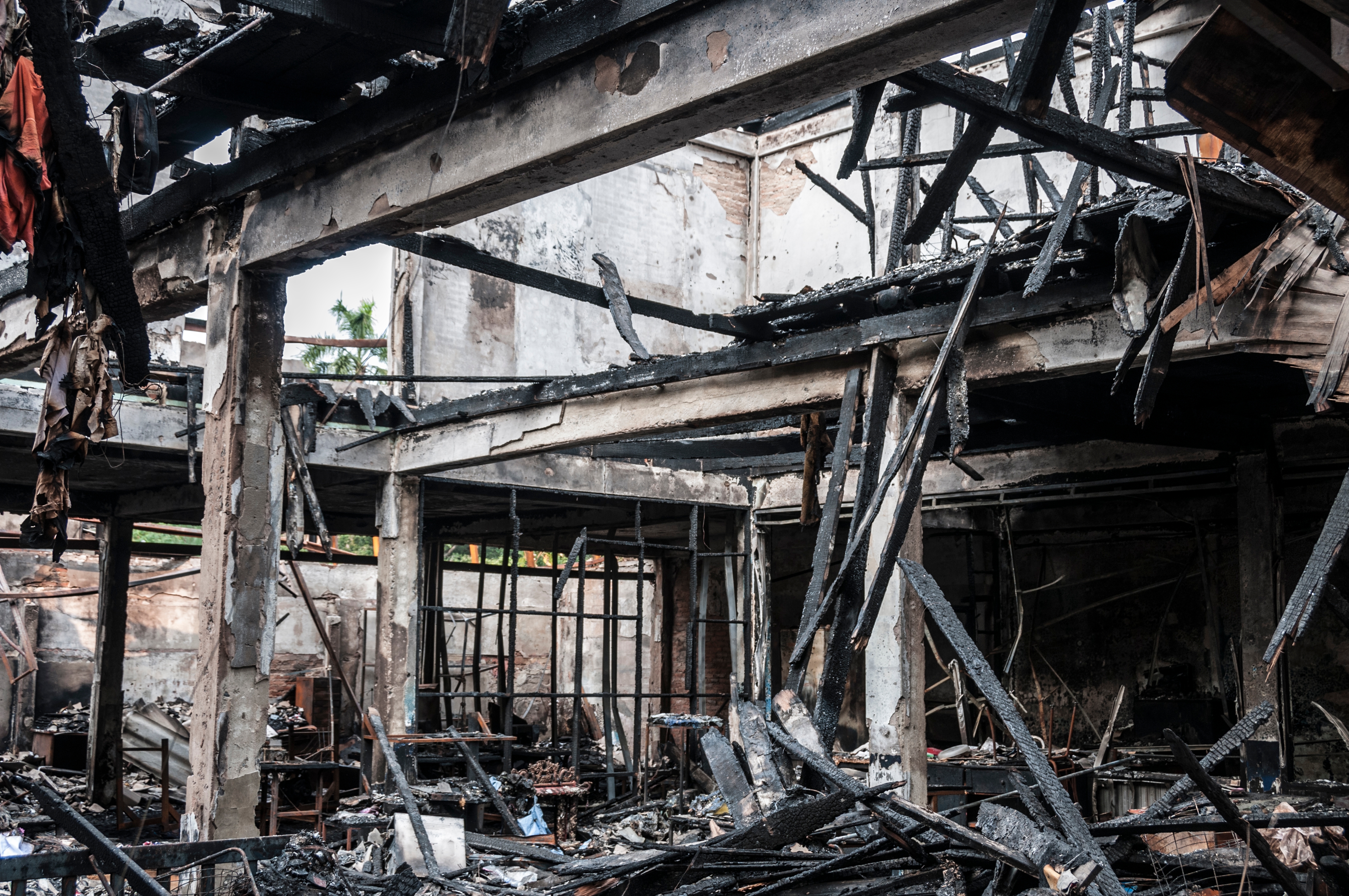 Rubble and charred remains of a building, showing extensive fire damage with collapsed beams and debris scattered throughout