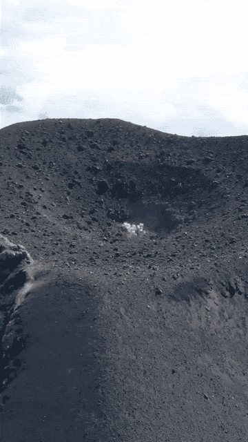 plume of smoke rises from volcano, then erupts into larger outpouring of smoke