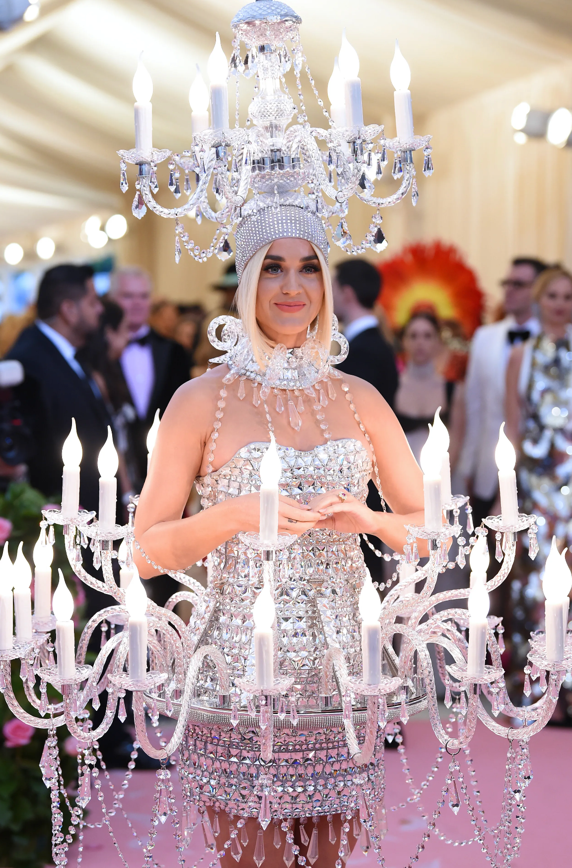 Persona en la alfombra roja, usando un vestido original estilo candelabro con cristales y luces sobre la cabeza