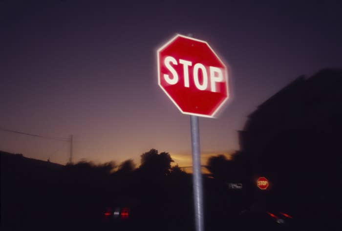 A stop sign at dusk, silhouetted against a darkening sky with a hint of sunset on the horizon
