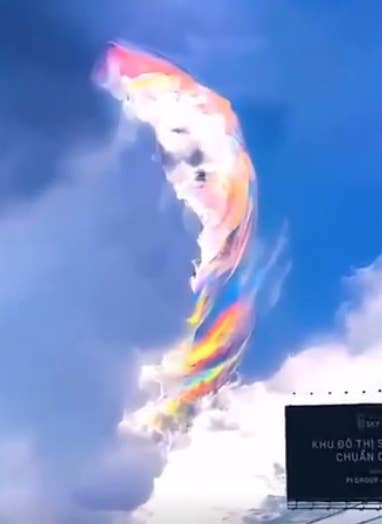 Clouds in the sky with a vibrant rainbow reflection; a partial billboard is visible below