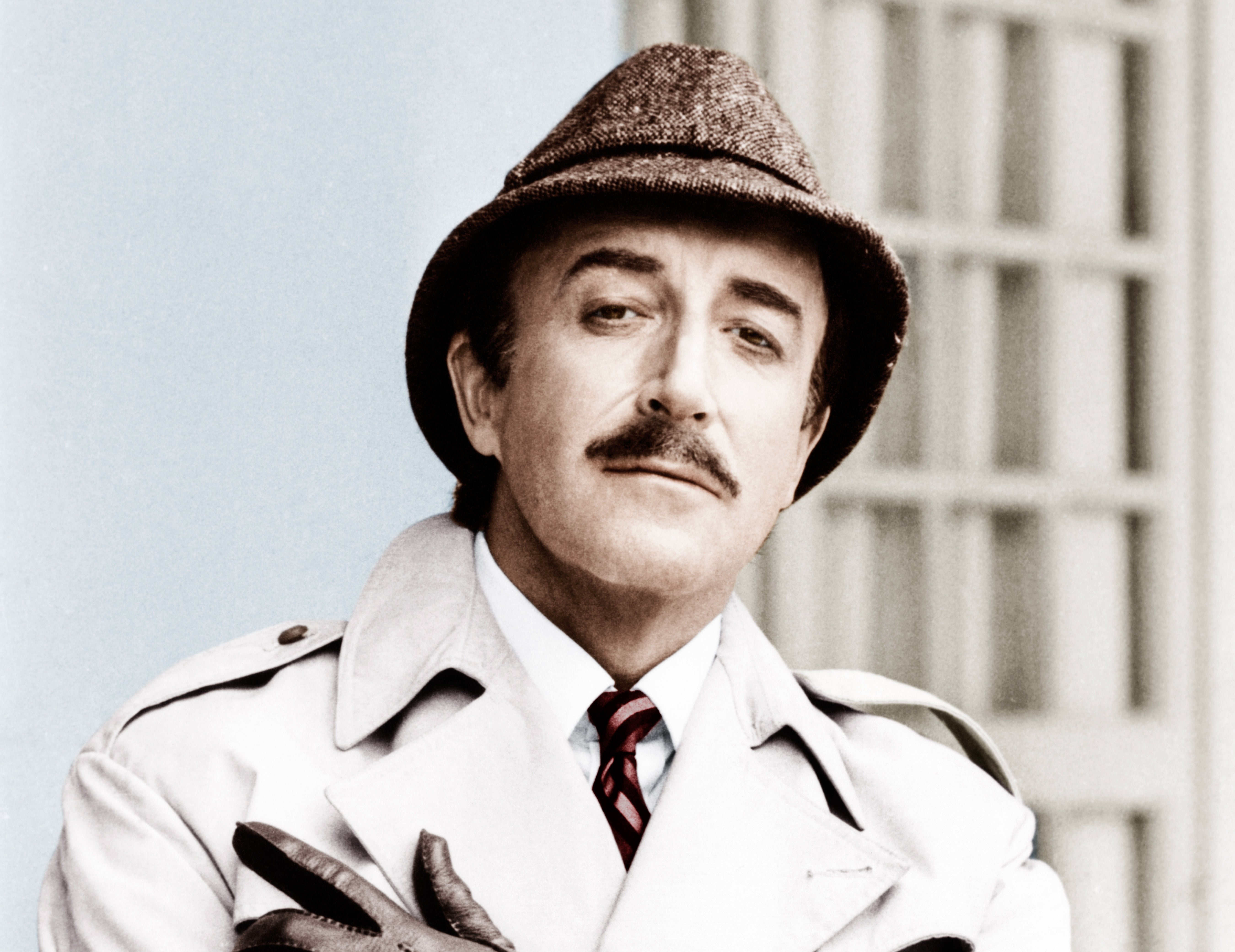 Person in a trench coat, tie, and hat poses confidently with crossed arms and gloved hands, evoking a classic detective style