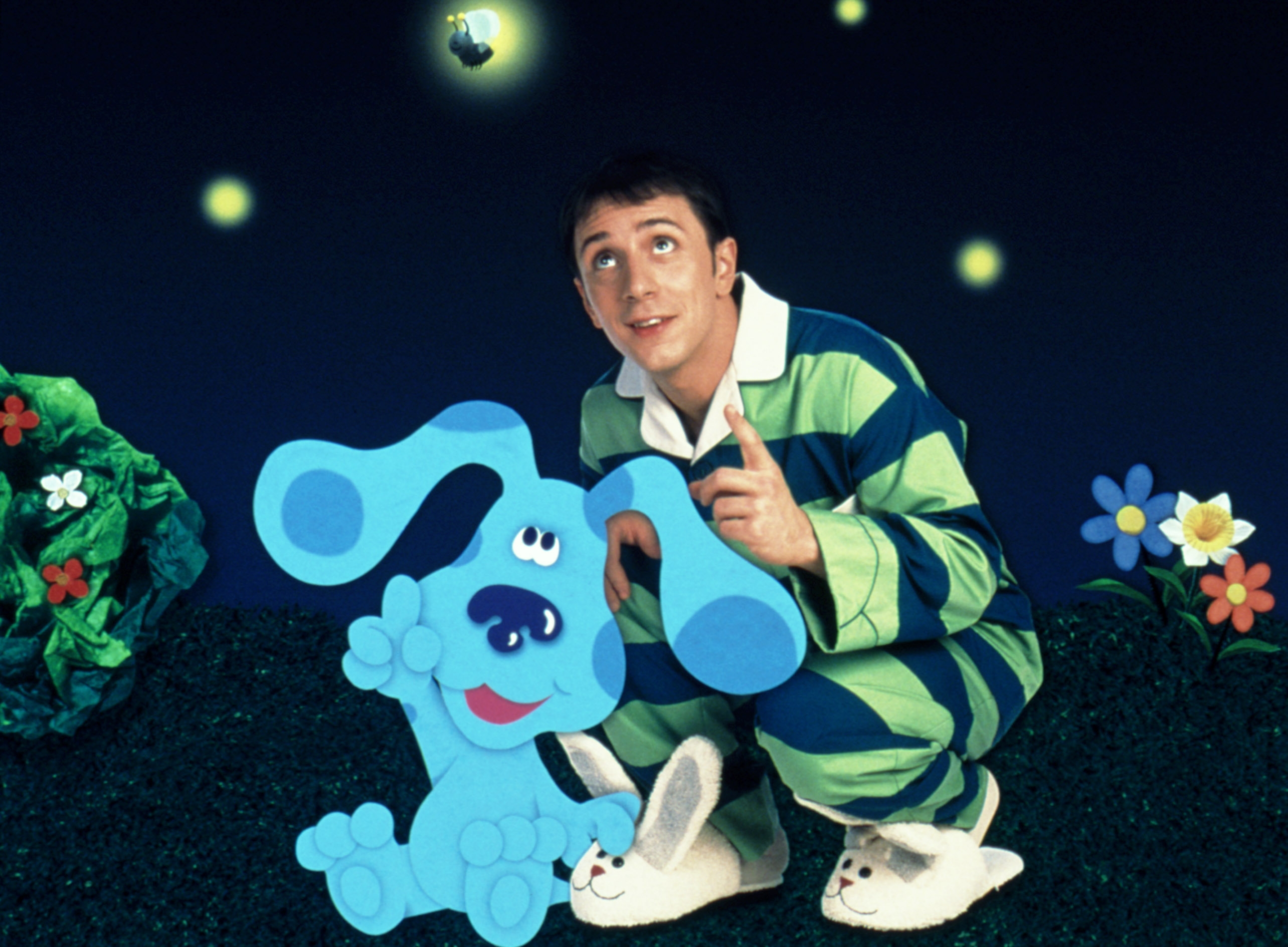 Person in striped outfit with cartoon dog in whimsical night setting, pointing at glowing sky