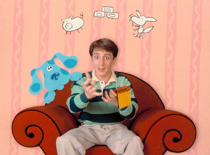 Person in a striped shirt sits on an armchair, holding a notebook, surrounded by cartoon characters including a dog and a pig