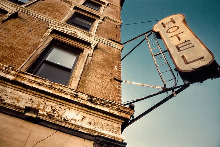 Old brick building with a weathered "HOTEL" sign on a metal frame, set against the sky