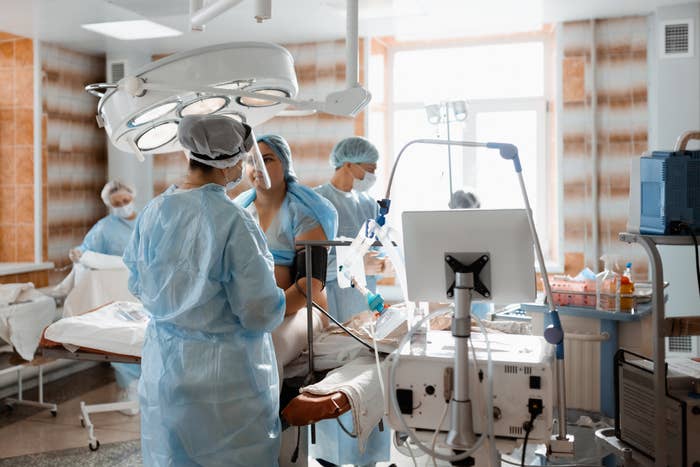 Medical team in surgical attire performing a procedure in a hospital operating room