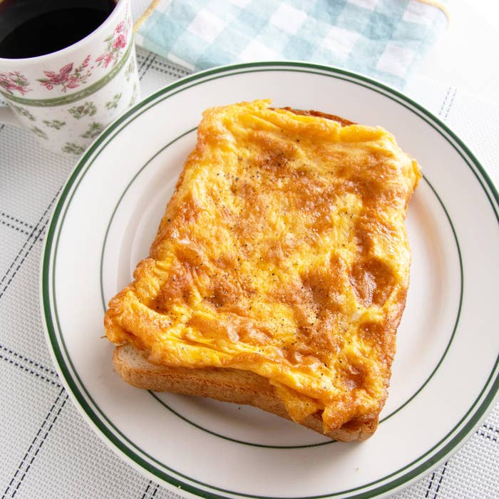 皿に乗ったトーストと卵焼きが載った朝食セット。隣にコーヒーカップが置かれている。