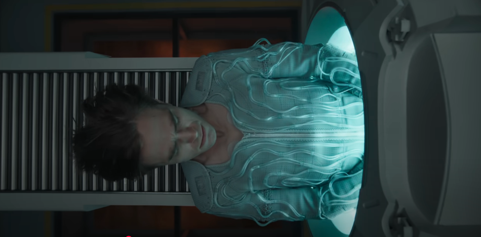Robert Pattinson sticking out of a tube in "Mickey 17," wearing a futuristic suit