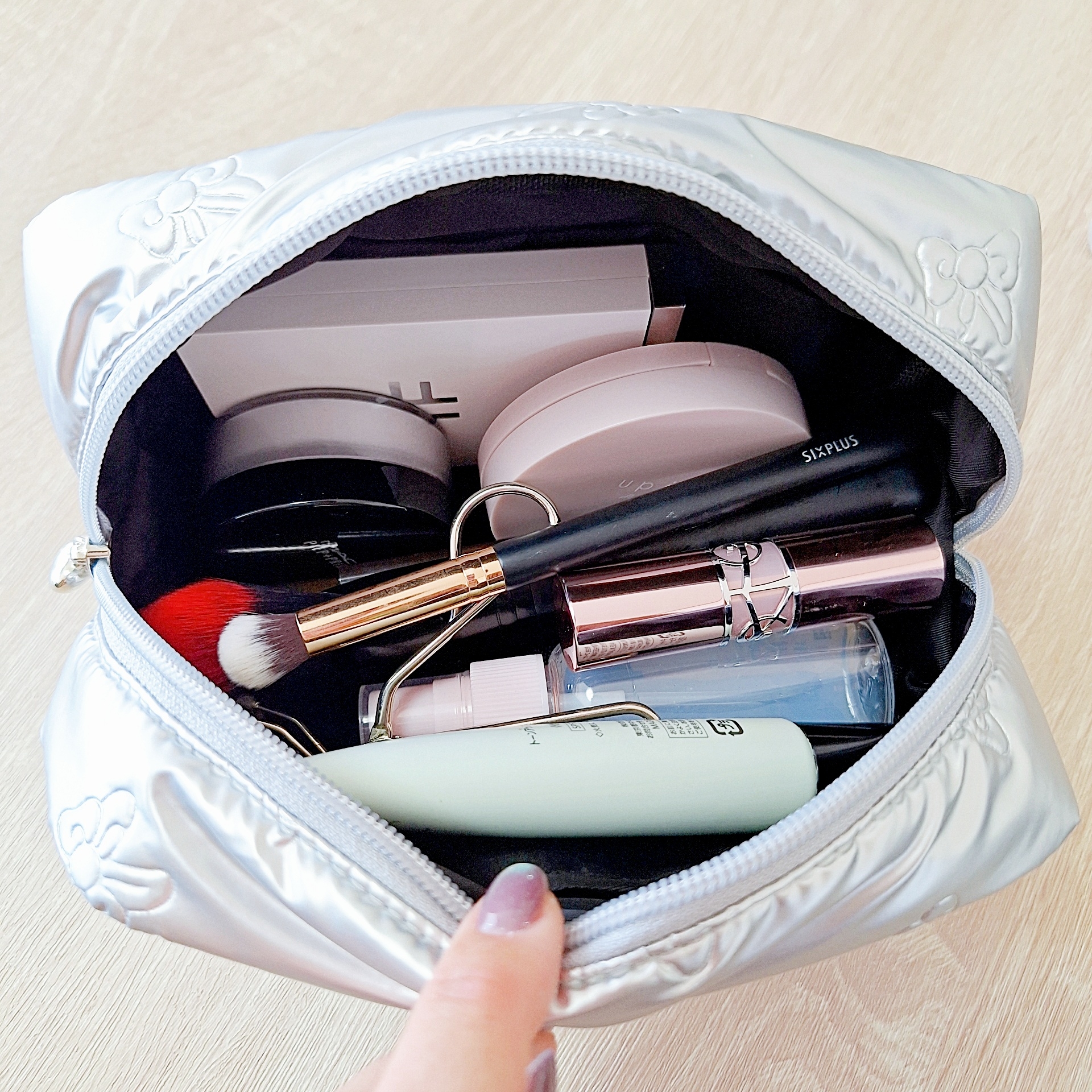 化粧ポーチの中に、化粧ブラシ、リップスティック、ファンデーションなどのメイク用品が収納されている様子。