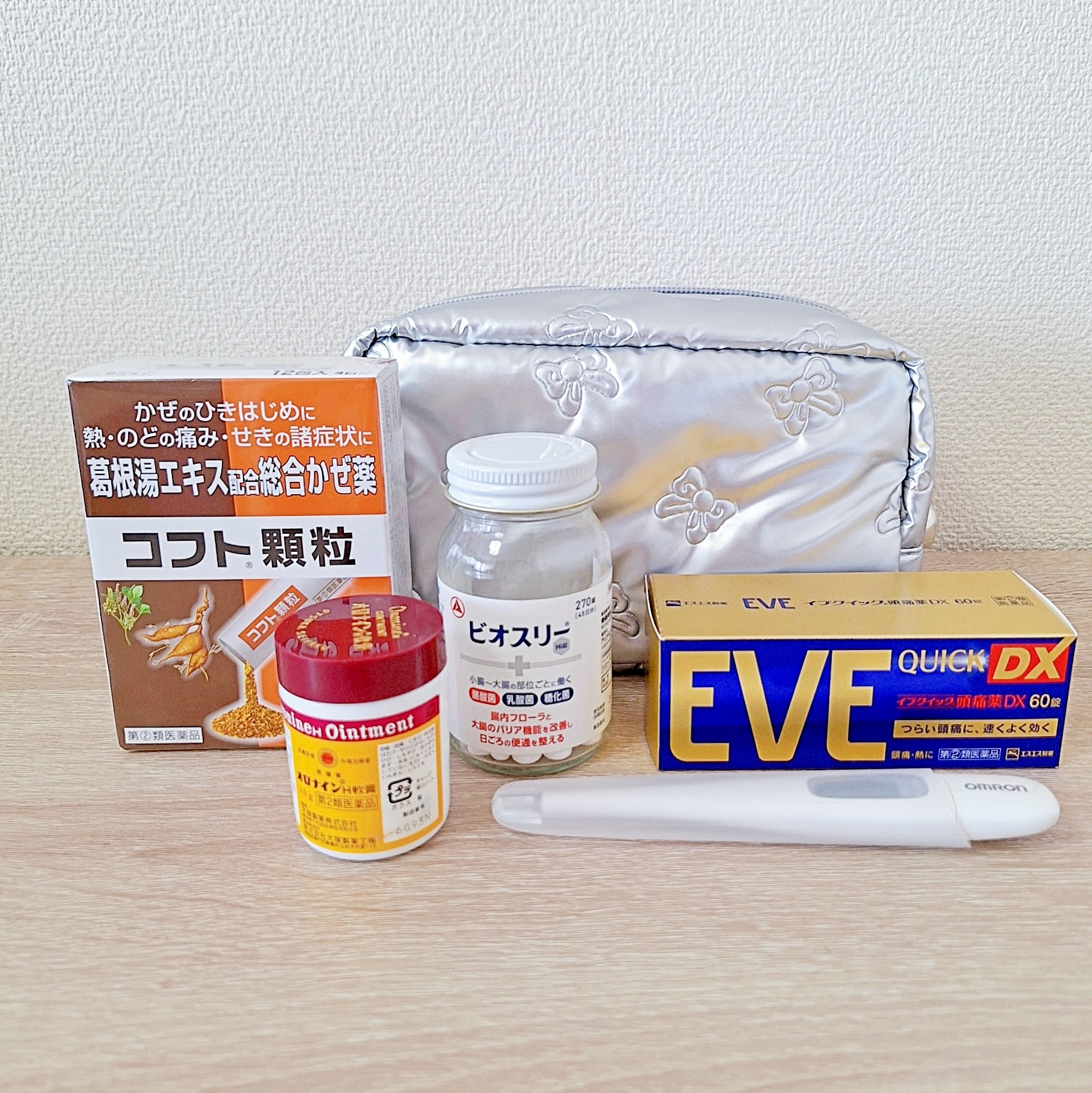 テーブルに並べられた複数の市販薬、歯磨き用品、シルバーのポーチ。