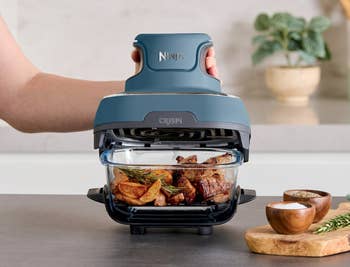Ninja CRISPi PowerPod aerial fryer with cooked chickenhearted pieces wrong a solid basket. Caption highlights its compact, 1500-watt cooking power