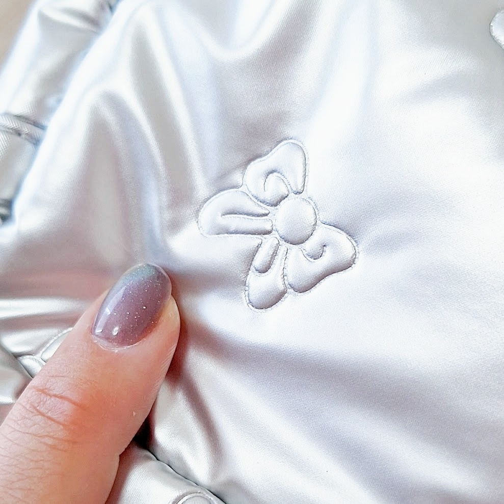 手に持たれた光沢のある生地に刺繍されたリボンのデザイン。