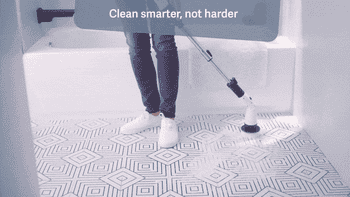 Person cleaning a tiled bath level with an electrical scrubber. Text reads,